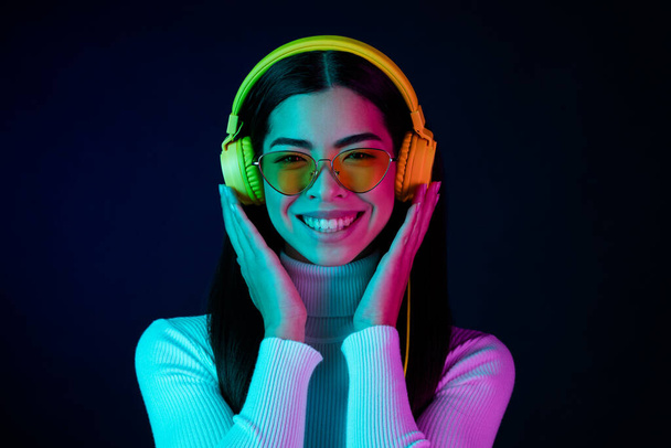 Photo of trend young millennial lady listen music wear spectacles headphones pullover isolated on black dark color background - Fotó, kép