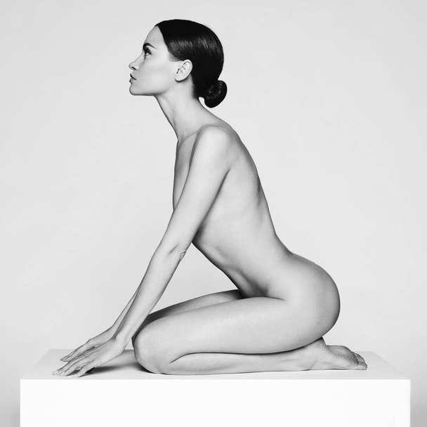 Art fashion studio portrait of beautiful brunette with short haircut. Young sexy model pose in white studio with naked body. Nude lady with classic professional make-up  - Φωτογραφία, εικόνα