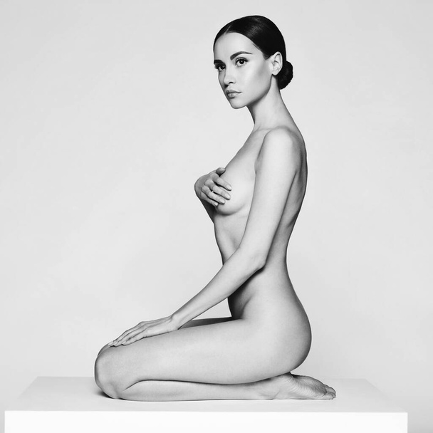 Művészet divat stúdió portré gyönyörű barna, rövid frizura. Fiatal szexi modell pózol fehér stúdióban meztelen testtel. Meztelen hölgy klasszikus professzionális sminkkel  - Fotó, kép