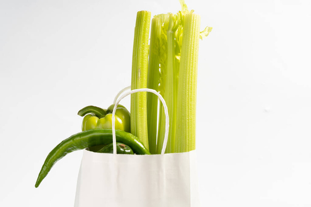 Доставка здоровой пищи фон. Веганская еда в бумажном пакете овощи белые, бэкграунд.. - Фото, изображение