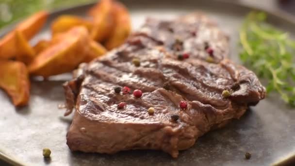 Délicieux steak de boeuf frais juteux avec des épices et des herbes sur un fond de béton foncé - Séquence, vidéo
