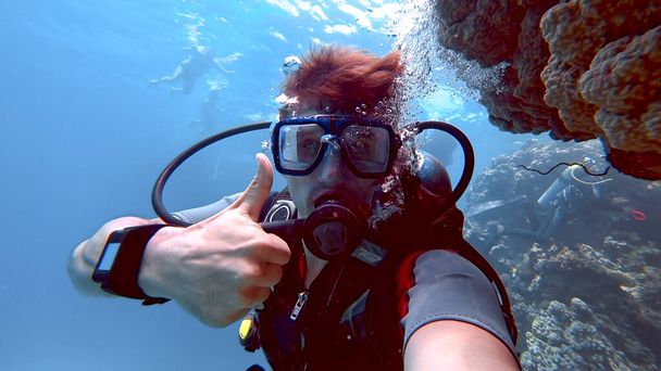 o mergulhador olha para a câmera e dá um polegar para cima - Foto, Imagem