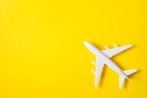 Flat lay design of travel concept with plane on yellow background with place for text. - Фото, изображение