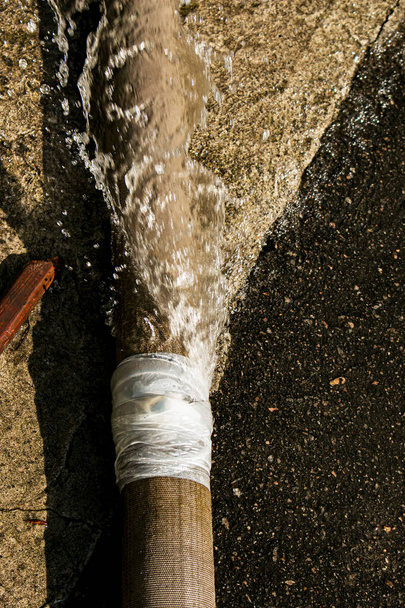 Tentative infructueuse d'éliminer les fuites dans l'union des tuyaux pour pomper l'eau de l'étang. Un trou dans un tuyau d'incendie d'où l'eau coule sous pression. - Photo, image