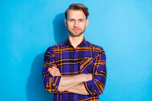 Photo of confident charming serious young man hold hands crossed wear plaid shirt isolated on blue color background - Fotó, kép