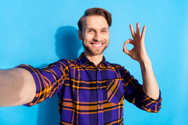 Photo of cheerful handsome guy make selfie fingers show okey approval symbol isolated on blue color background - Zdjęcie, obraz
