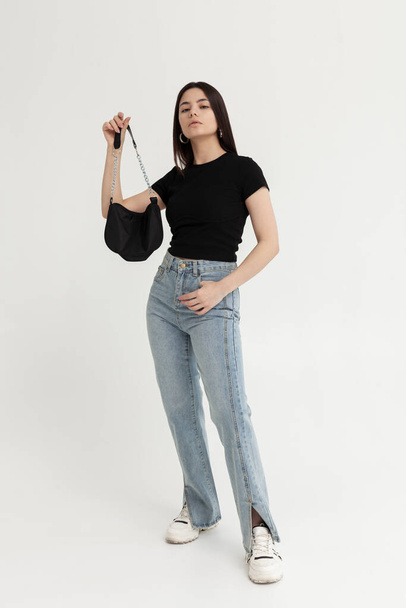 beautiful girl in fashionable jeans and with a bag in her hands - Photo, image