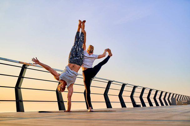 Couple doing practicing yoga together on nature outdoors . Morning exercises at the sunrise. - Photo, Image