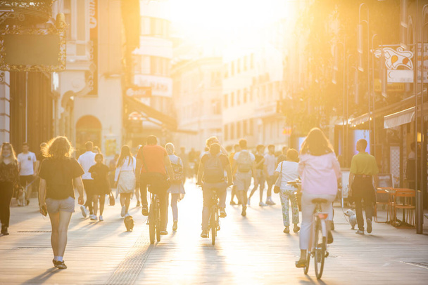 Θολωμένο πλήθος κόσμου στον πεζόδρομο Κοπόβα στη Λιουμπλιάνα το ηλιοβασίλεμα. Αστικός τρόπος ζωής και κινητικότητα έννοια. - Φωτογραφία, εικόνα