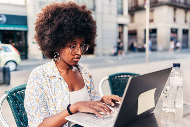 african american young woman working remotely from a bar terrace - Foto, Imagen