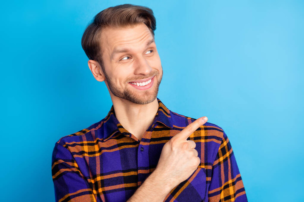 Photo of charming happy young old man look point finger empty space sale isolated on blue color background - 写真・画像