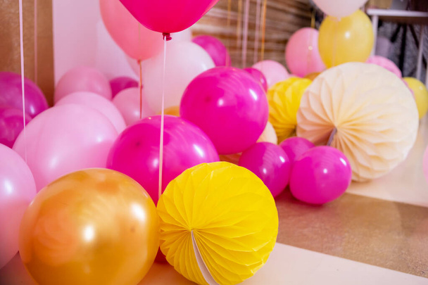Roze en witte ballonnen in de ontvangstruimte.Ballonnen gevuld met helium, witte en gouden kleuren, gebonden met gouden linten. Vliegende ballen, als een essentieel accessoire voor het vieren van verjaardag en andere feestdagen. - Foto, afbeelding