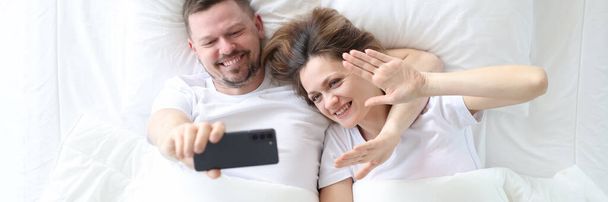 Mężczyzna i kobieta leżący w łóżku i biorąc selfie widok z góry - Zdjęcie, obraz