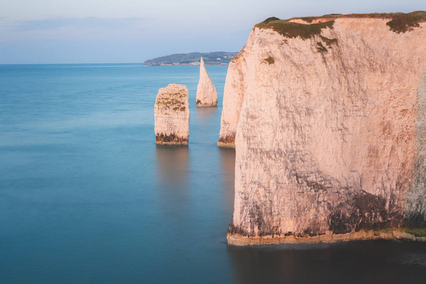 Sunset or sunrise golden hour light over seascape landscape of the white chalk cliffs and sea stacks of Old Harry Rocks on the Jurassic Coast in Dorset, England, UK. - Photo, Image