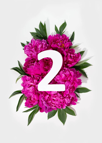 Diseño con flores de peonías rosadas y signo número dos. Acostado. Vista desde arriba. - Foto, Imagen