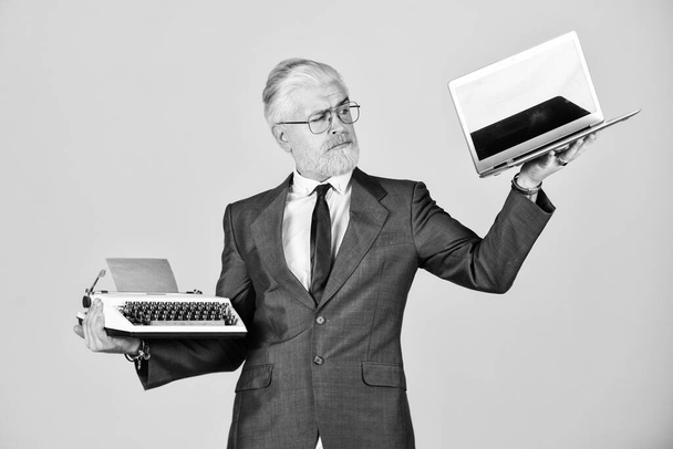 Buy new modern gadget. Useful device. Modern instead outdated. Connoisseur of vintage values. Typewriter against laptop. Businessman use modern technology. Man dyed beard hair yellow background - Fotó, kép