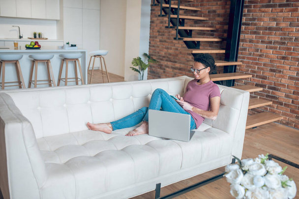 A woman in casual clothes surfing internet while resting at home - Foto, afbeelding