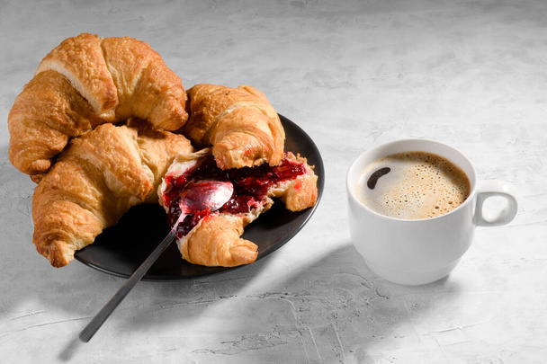 Croissant francese fresco con marmellata di ciliegie su piatto grigio e cau di caffè fresco - Foto, immagini