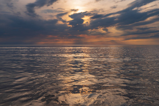 sunset in the sea with clouds and calm water on the surface of which sunlight reflects by creating a light path - Foto, Imagen