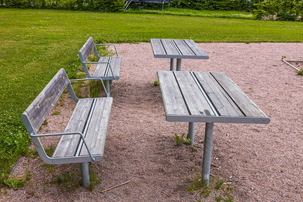 Krásná krajina pohled na dřevěné lavice a stoly venkovní v blízkosti hřiště pro děti. - Fotografie, Obrázek