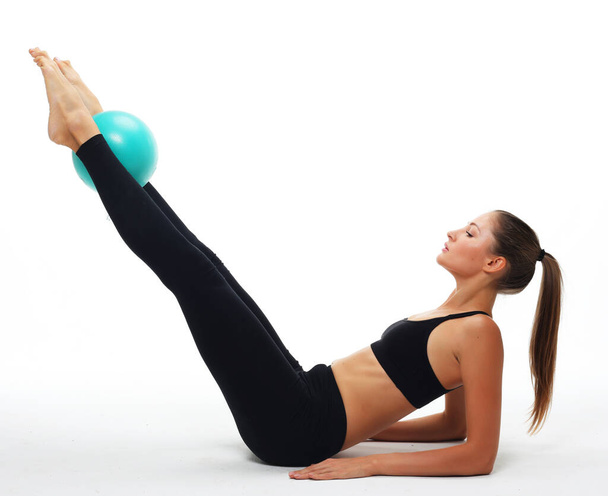 Young fit adult woman doing yoga exercise workout with gymnastics ball. - 写真・画像