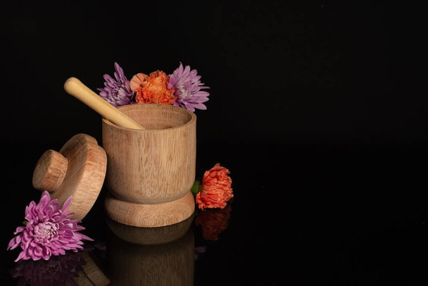 Wooden bowl with honey dipper dripping honey with flowers isolated in black background - Photo, Image