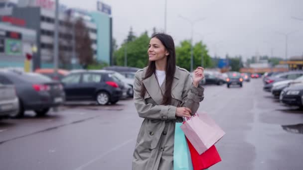 Vrouwelijke shopaholic met tassen lopen langs parkeerplaats naar haar auto - Video