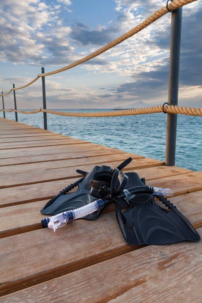 Maschera subacquea, nuotate e uno snorkeling su un molo di legno con un mare sullo sfondo. Viaggio e concetto di vacanza. - Foto, immagini