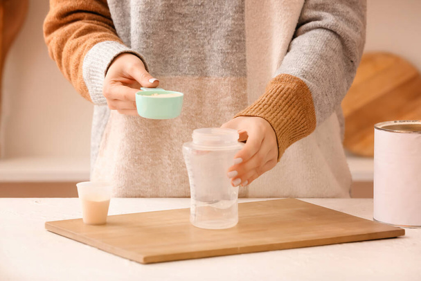 Woman preparing baby milk formula in kitchen - Photo, image