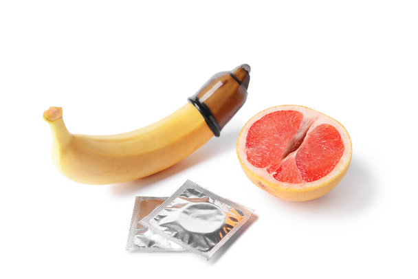 Banán a grapefruit s kondomy na bílém pozadí. Erotický koncept - Fotografie, Obrázek