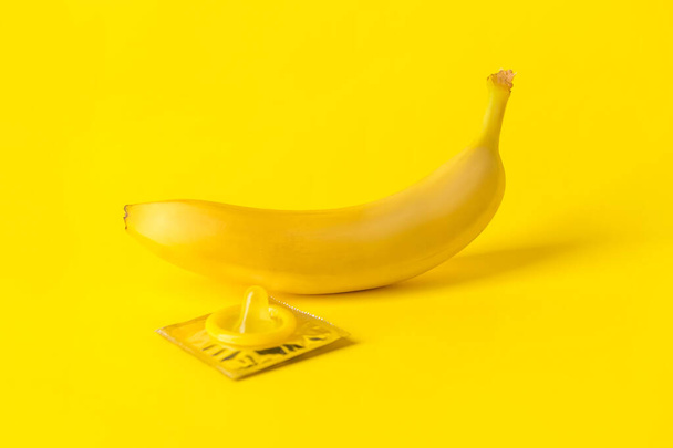 Банан с презервативами на цветном фоне. Эротическая концепция - Фото, изображение