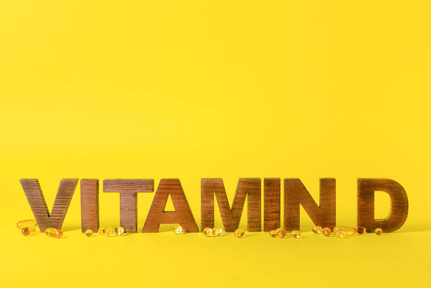 Κείμενο VITAMIN D με χάπια στο φόντο χρώμα - Φωτογραφία, εικόνα
