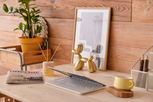 Moderne werkplaats met laptop en foto bij houten muur - Foto, afbeelding