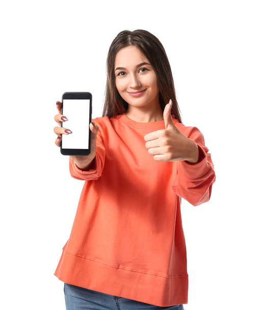jonge vrouw met mobiele telefoon tonen duim-up op witte achtergrond - Foto, afbeelding