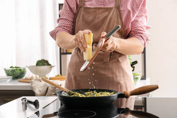 女性は台所でほうれん草とチーズとおいしいパスタを調理 - 写真・画像