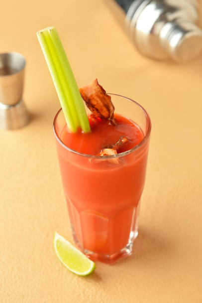 Glass of bloody mary cocktail garnished with bacon and celery on color background - Photo, Image
