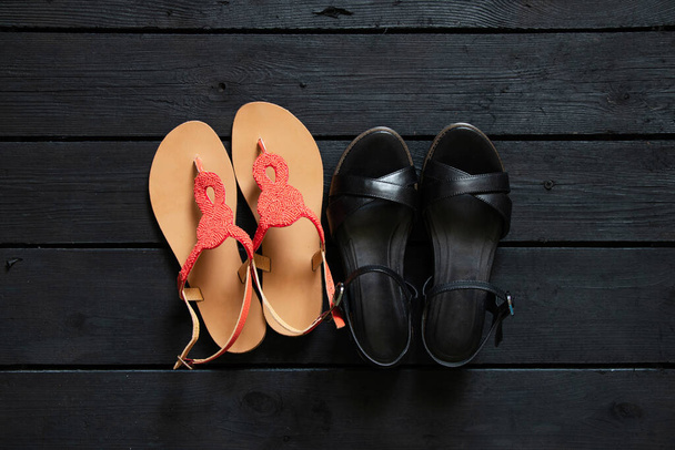 vrouwen zomer sandalen op zwarte houten vloer thuis, vrouwen schoenen op de vloer - Foto, afbeelding