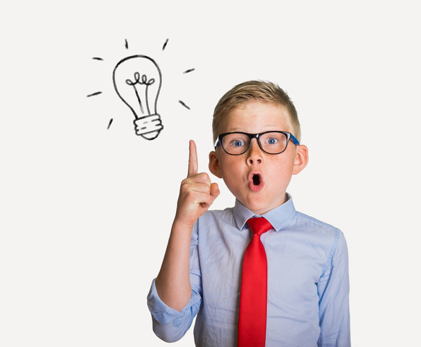 Child with light bulb. Boy in glasses is surprised with finger up. Have an idea. Amazed blond child in eyewear with open mouth and big eyes isolated on white background. Shocked kid go back to school - Foto, Bild