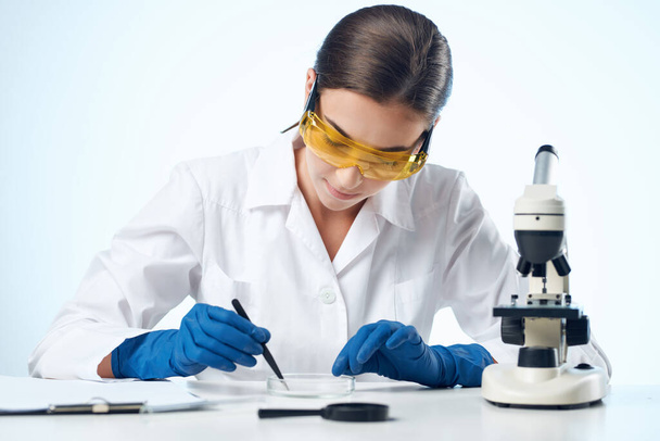 Vrouw in witte jas laboratorium microscoop onderzoek biotechnologie - Foto, afbeelding