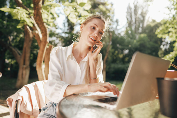 Young successful businesswoman using laptop for work outdoors - Fotó, kép