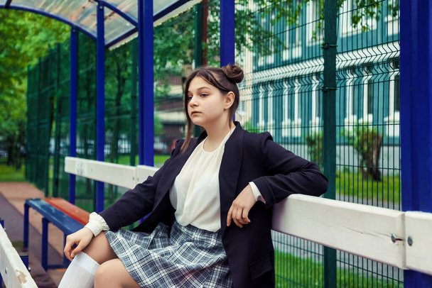 Art noise film style image. Portrait of thirteen-year-old schoolgirl in white blouse, plaid skirt and jacket at school. Emotional teen girl posing looking at camera. Concept of school age and learning - Фото, изображение