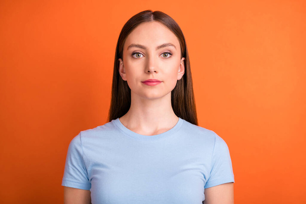 Photo of nice serious brunette hair young lady wear blue t-shirt isolated on vivid orange color background - Fotoğraf, Görsel