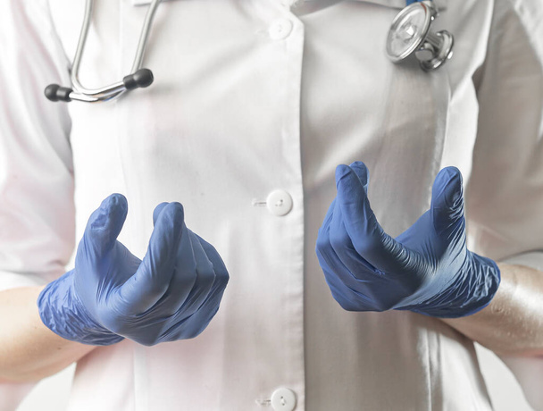 Az orvos kesztyűs kézzel magyarázza az smth-t. Orvosszakértő egyenruhában sztetoszkóppal közelről az orvosi konzultáció során - Fotó, kép