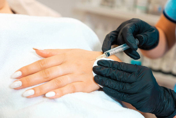 Косметолог делает инъекции ботулинового токсина на руку клиента против гипергидроза. Закрывай. Процедура в салоне красоты. - Фото, изображение