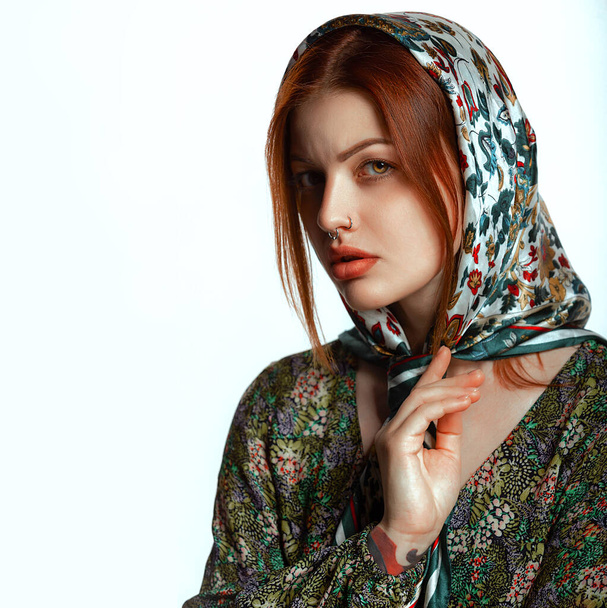 Egy piercinges orrú és divatos fejkendős fiatal nő portréja. Fehér háttér, hely a szövegnek. Szépség, divat koncepció. - Fotó, kép