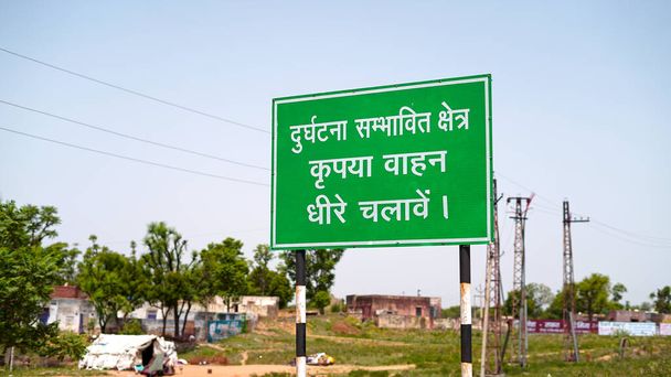 Προειδοποιητική πινακίδα με γραπτή γλώσσα χίντι. Οδική πινακίδα για να γνωρίζουν οι άνθρωποι να πηγαίνουν αργά σε κατοικημένη περιοχή. - Φωτογραφία, εικόνα