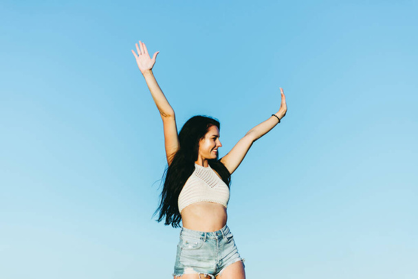 Cute young girl raised his hands up and smiling.Happiness in lifestyle.Inspiration in nature.People success,victory,and power.woman with hands up on blue background.Toned - Fotografie, Obrázek