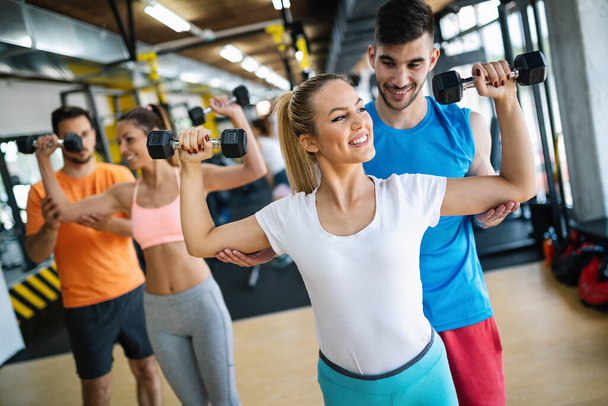 Group of young fit people doing exercises in gym to stay healthy. Sport, friend, workout concept - Foto, Bild
