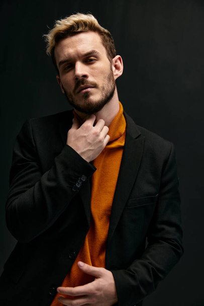 man in orange sweater and black coat gesturing with hands cropped view - Foto, Bild