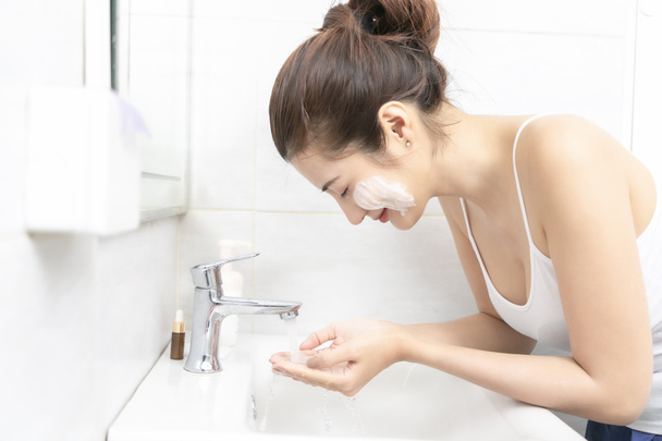 Jovem mulher asiática lavar o rosto no banheiro. - Foto, Imagem